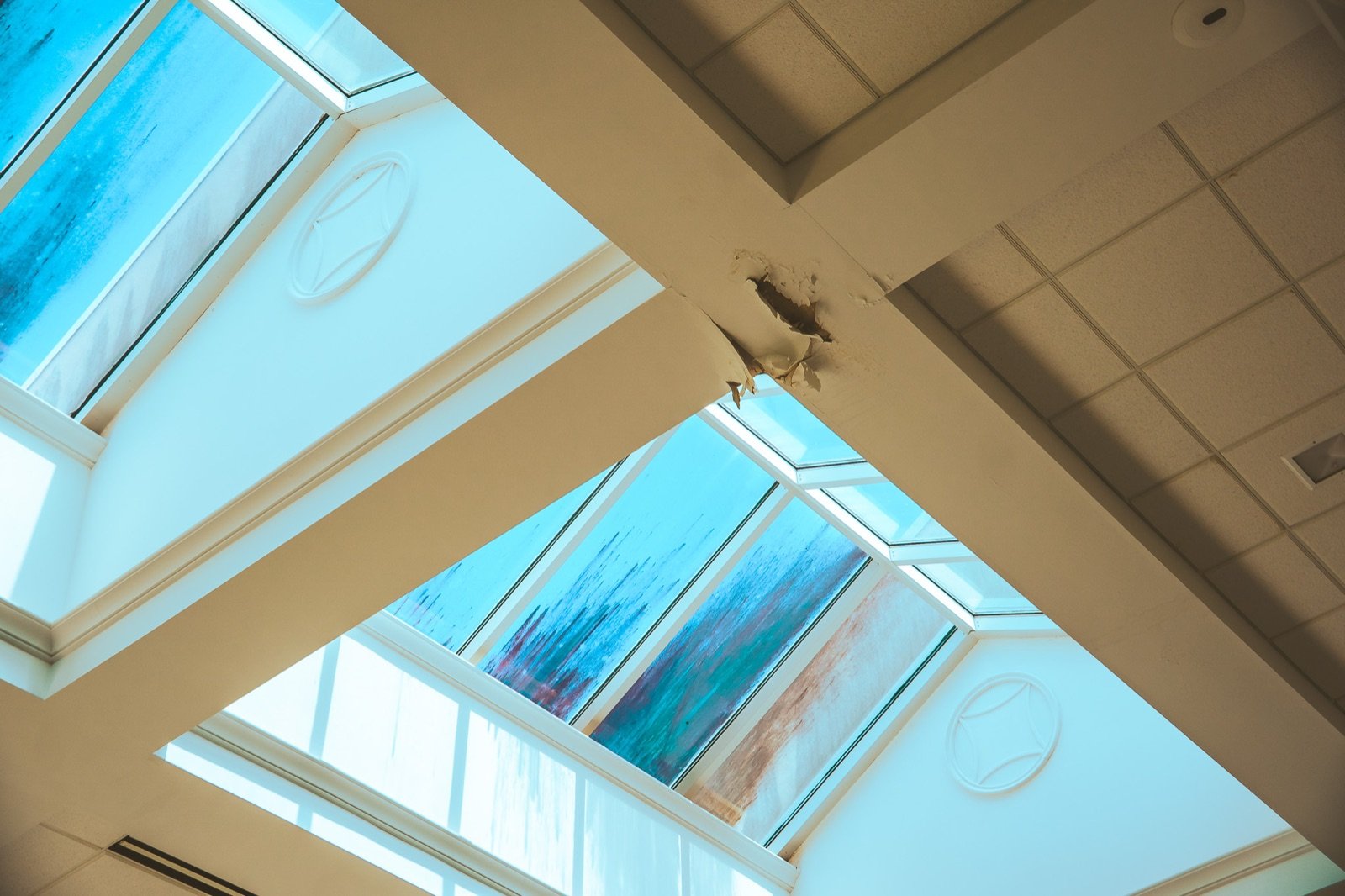 The atrium skylights before repair: heavy water staining on the glass and a hole where the sheetrock below had failed